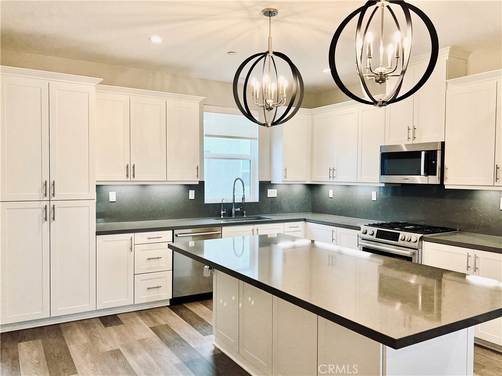 2336 Synergy Irvine, CA 92614 - Photo 8 of 24 a kitchen with stainless steel appliances granite countertop a sink a stove and a wooden floors