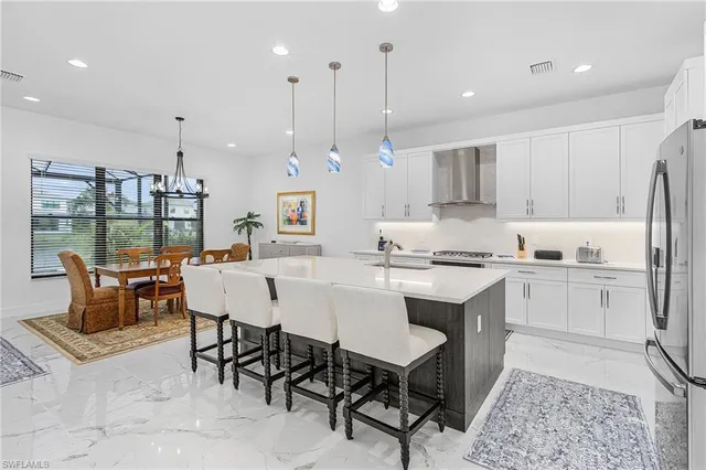 a kitchen with stainless steel appliances granite countertop a table chairs sink and cabinets