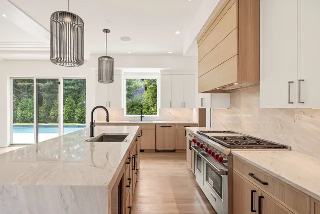 a kitchen with stainless steel appliances granite countertop a sink a stove a refrigerator and island with wooden floor