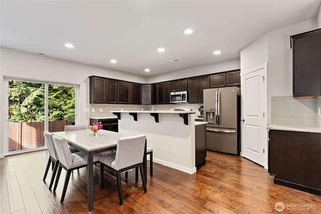 a kitchen with stainless steel appliances a dining table chairs microwave and refrigerator