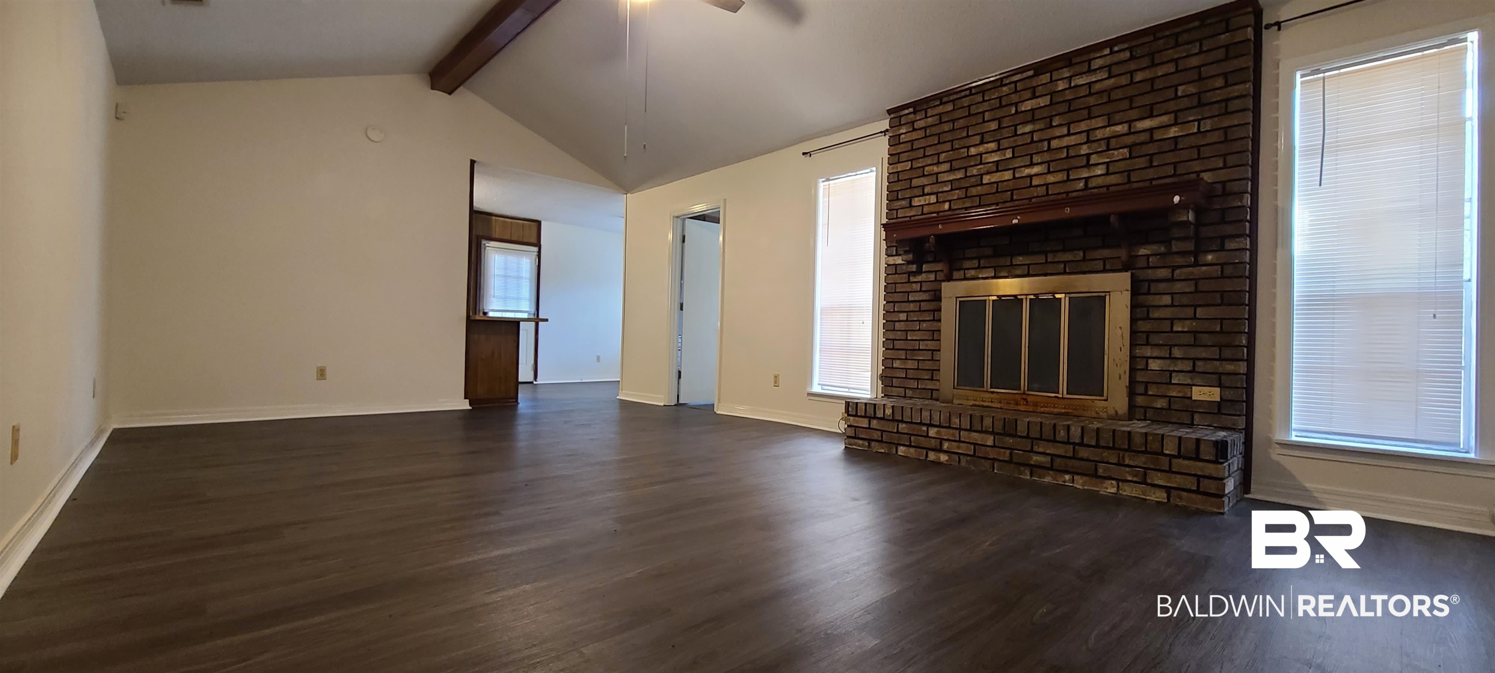 5305 Wilhelm Drive Mobile, AL 36618 - Photo 3 of 16 Unfurnished living room featuring baseboards, lofted ceiling with beams, ceiling fan, and wood finished floors