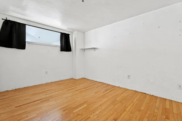 a view of empty room with wooden floor and windows