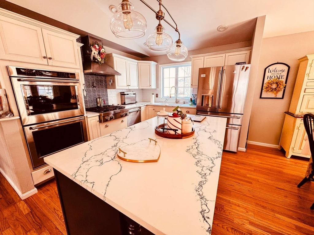 70 Brown Street Fall River, MA 02724 - Photo 3 of 31 a kitchen with stainless steel appliances kitchen island granite countertop a refrigerator a stove and a dining table with wooden floor