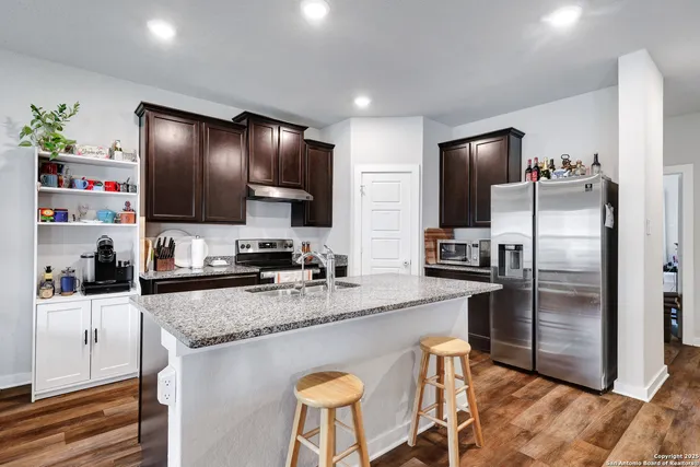a kitchen with granite countertop a refrigerator stove microwave and sink