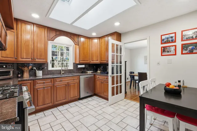 a kitchen with stainless steel appliances kitchen island granite countertop a sink cabinets and window