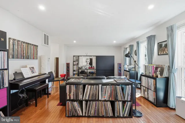 a living room with furniture a flat screen tv and a refrigerator