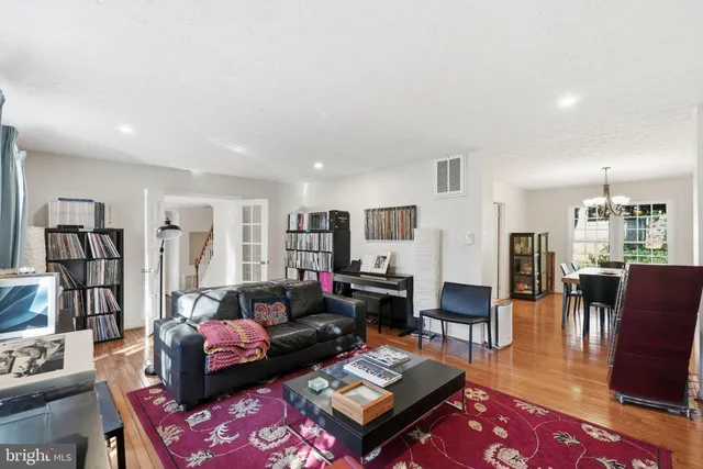 a living room with furniture couches and a dining table with wooden floor