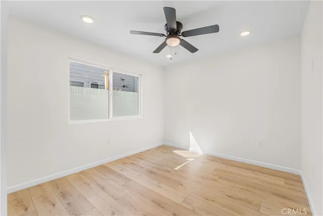 a view of empty room with wooden floor and fan