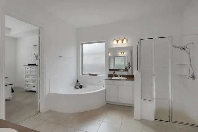 a spacious bathroom with a tub a double vanity sink and mirror