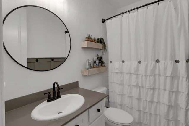 a bathroom with a sink a toilet and a mirror