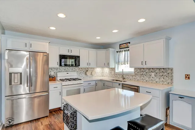 a kitchen with stainless steel appliances a sink a stove a refrigerator and cabinets