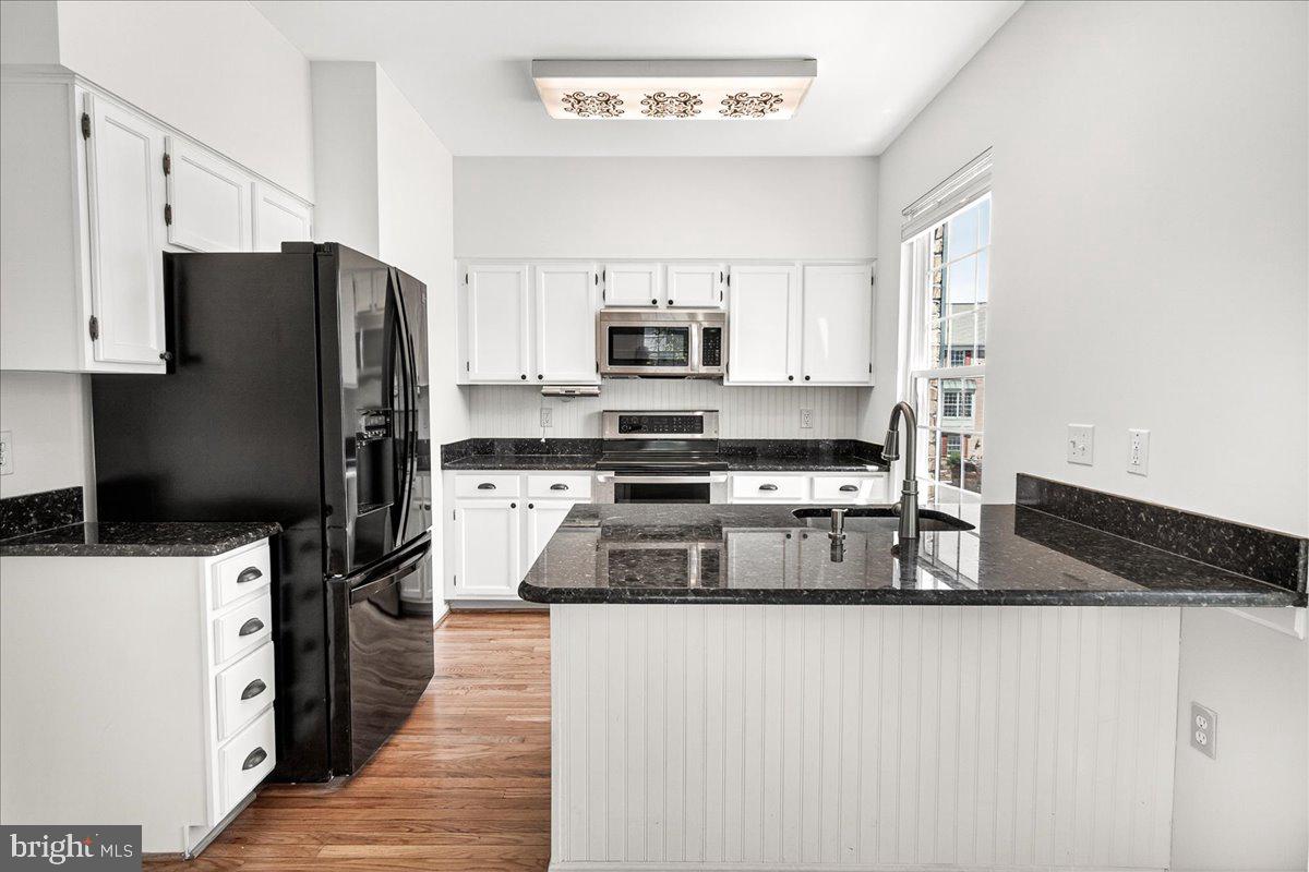 111 Water Land Way Frederick, MD 21702 - Photo 19 of 35 a kitchen with granite countertop a refrigerator and a stove top oven