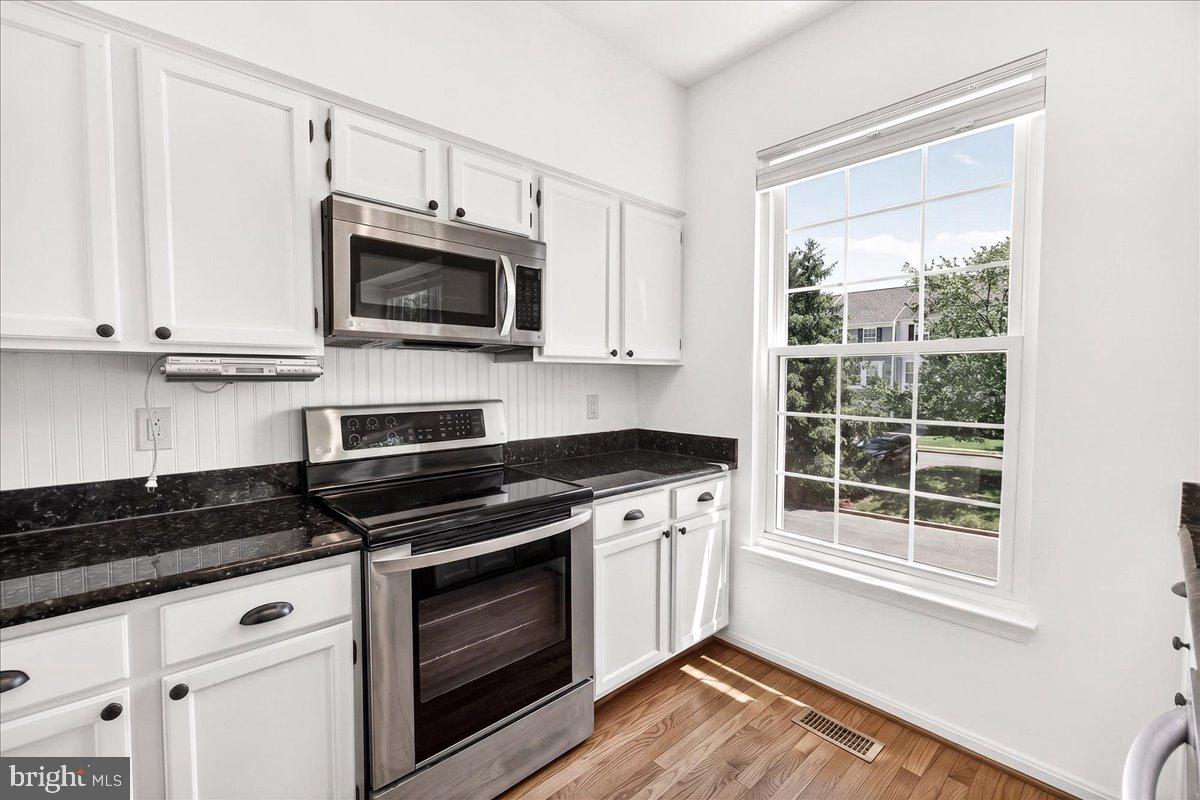 111 Water Land Way Frederick, MD 21702 - Photo 20 of 35 a kitchen with stainless steel appliances granite countertop a stove a microwave and a white cabinets