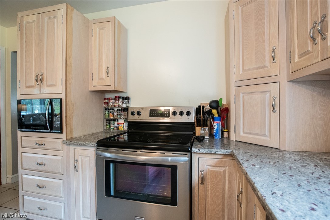 20873 Drake Road Strongsville, OH 44149 - Photo 13 of 25 Kitchen featuring stone countertops, tile flooring, and stainless steel range with electric cooktop