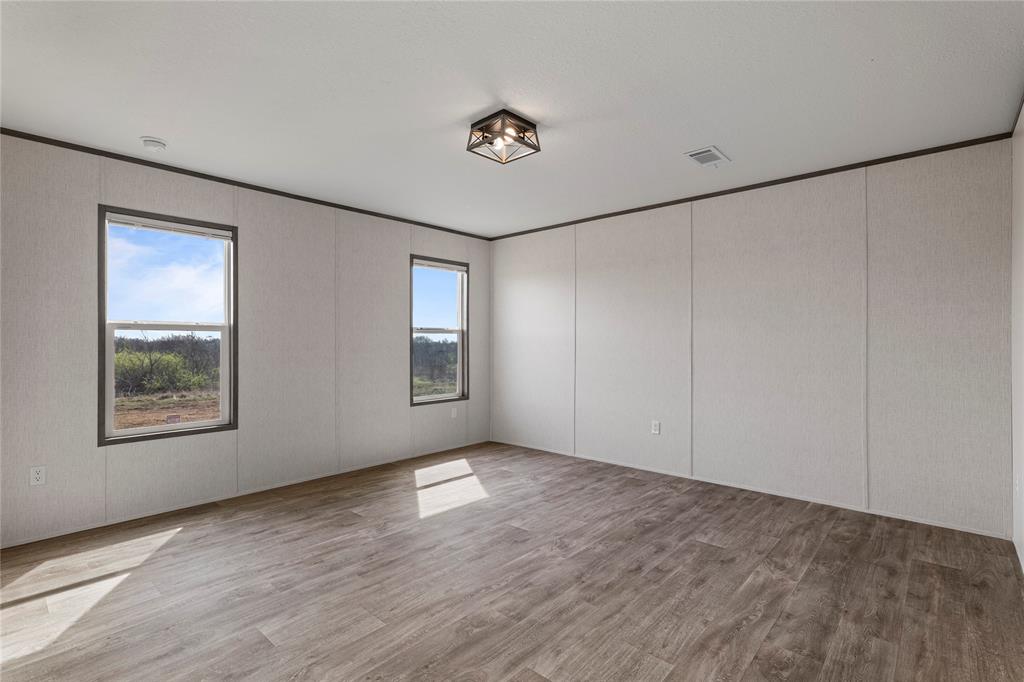 3888 Sandusky Road Whitesboro, TX 76273 - Photo 11 of 24 Unfurnished room featuring light wood-style flooring, crown molding, and a decorative wall