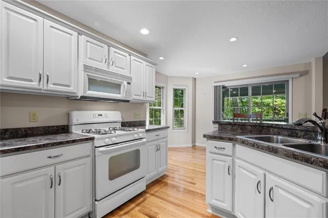 a kitchen with granite countertop white cabinets and white appliances