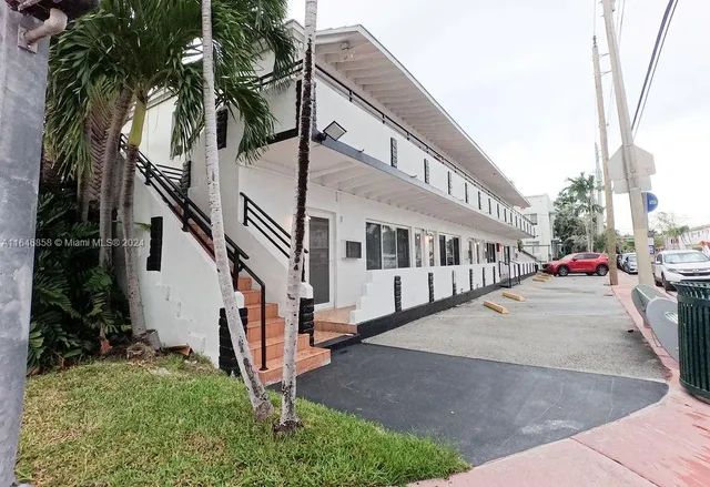 a view of a white house with a large windows and a small yard