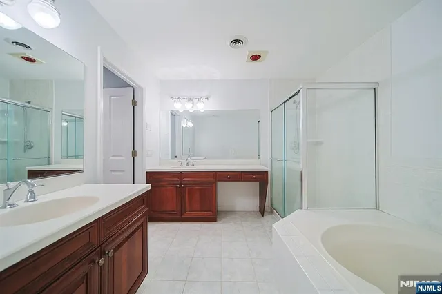 a spacious bathroom with a tub sink shower and mirror