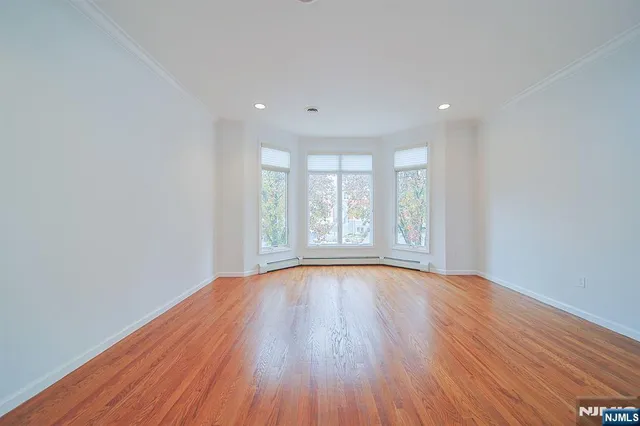 a view of an empty room with wooden floor and window