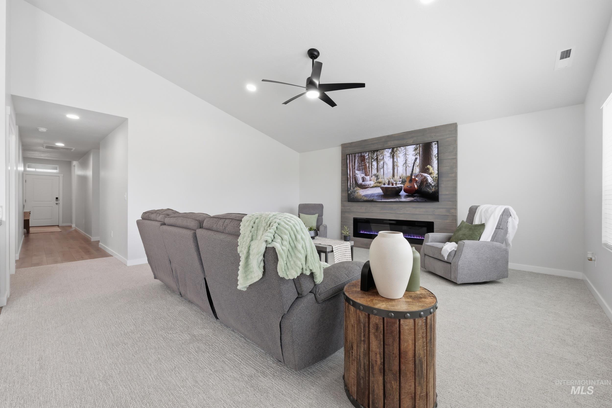 3665 W Lane Meridian, ID 83642 - Photo 17 of 42 Vaulted ceiling living area featuring an electric fireplace with a stacked wood-finish surround, recessed lighting, and a ceiling fan