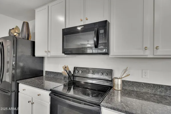 a kitchen with granite countertop white cabinets and refrigerator