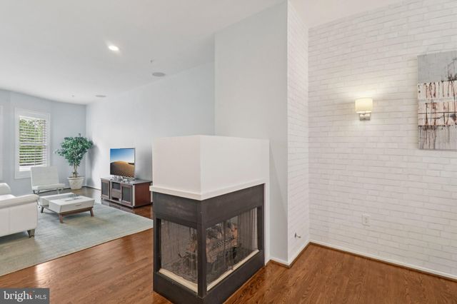 a living room with couches and kitchen view with wooden floor
