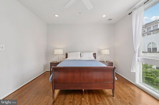 a view of a hallway with wooden floor and a bathroom