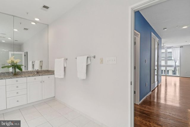 a spacious bathroom with a granite countertop sink a toilet a large mirror and shower