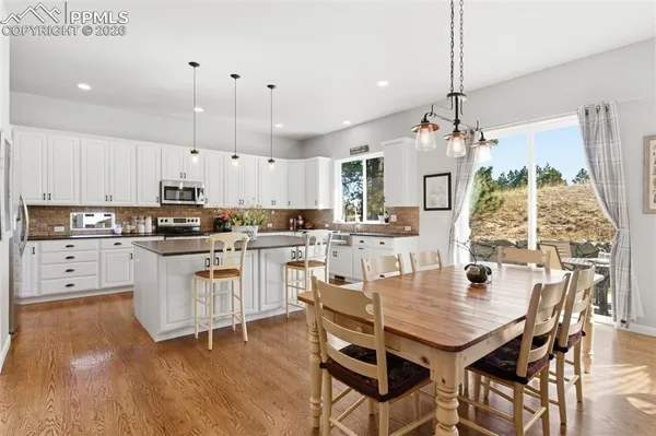 a kitchen with stainless steel appliances granite countertop a stove top oven a refrigerator a sink and white cabinets with wooden floor