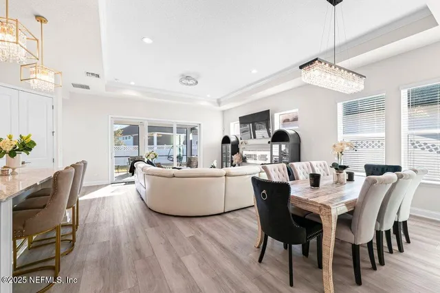 a dining room with wooden floor and a chandelier