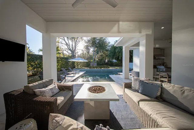 a view of a patio with couches table and chairs under an umbrella with a small yard