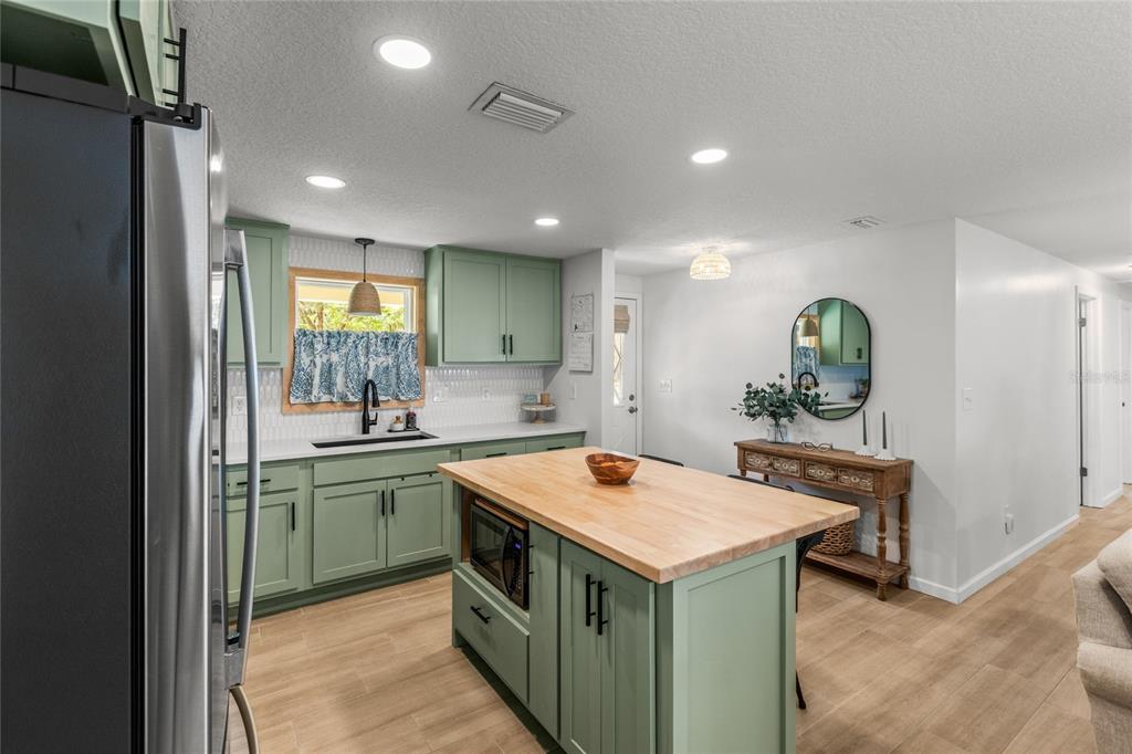 5921 County Road 352 Keystone Heights, FL 32656 - Photo 32 of 73 a kitchen that has a sink a microwave oven a stove and white cabinets with wooden floor
