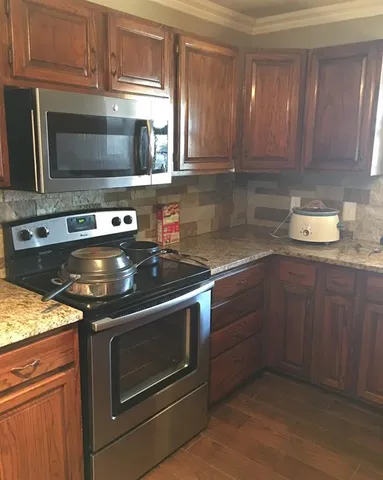 a kitchen with granite countertop a stove microwave and oven