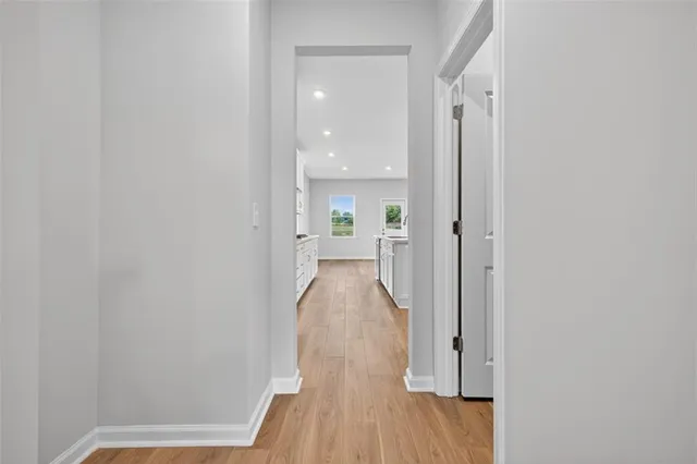 a view of a hallway with wooden floor and a bathroom