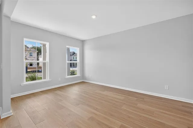 a view of an empty room with wooden floor and windows