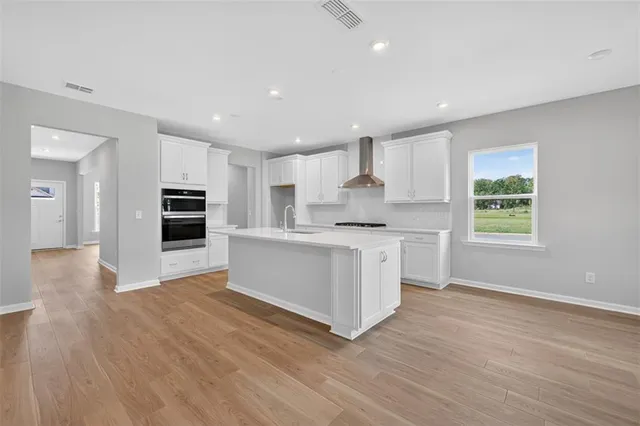 a kitchen with stainless steel appliances kitchen island wooden floors and white cabinets