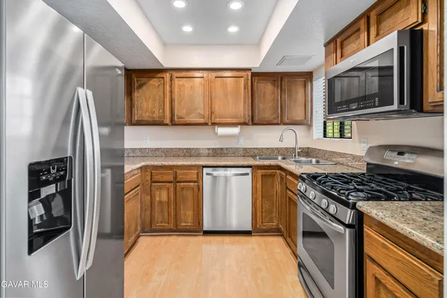 a kitchen with stainless steel appliances granite countertop a stove a sink and a microwave