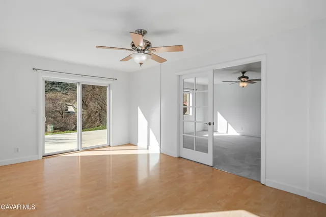 an empty room with windows and ceiling fan
