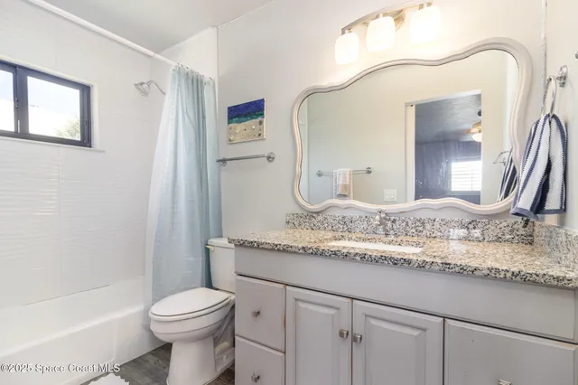 a bathroom with a granite countertop sink a toilet and a mirror