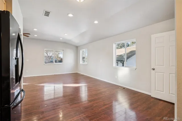 an empty room with wooden floor and a flat screen tv