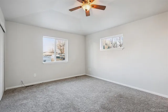 an empty room with a window and a ceiling fan