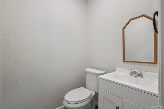 a bathroom with a toilet sink vanity and mirror