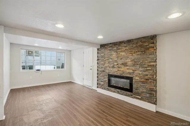 an empty room with wooden floor fireplace and windows
