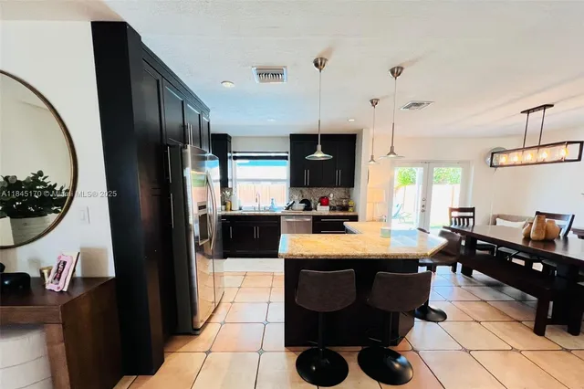 a kitchen with stainless steel appliances kitchen island granite countertop a refrigerator a stove a sink and dishwasher with a dining table