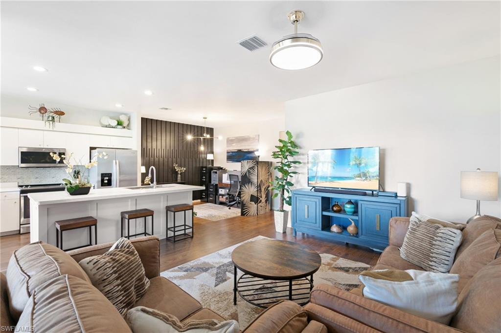 21445 Knighton Run Estero, FL 33928 - Photo 19 of 48 a living room with furniture a flat screen tv and kitchen view