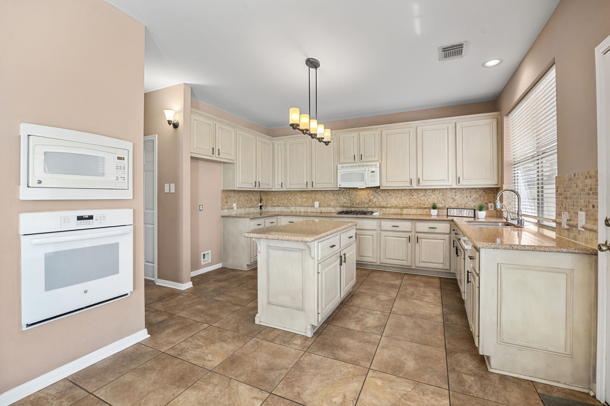 20407 Spring Rose Drive Katy, TX 77450 - Photo 13 of 33 The kitchen offers plenty of space for cooking, with abundant cabinet storage and a central island for added functionality. Granite countertops provide a sleek, durable finish, while pendant lighting adds a stylish touch to this inviting culinary space.