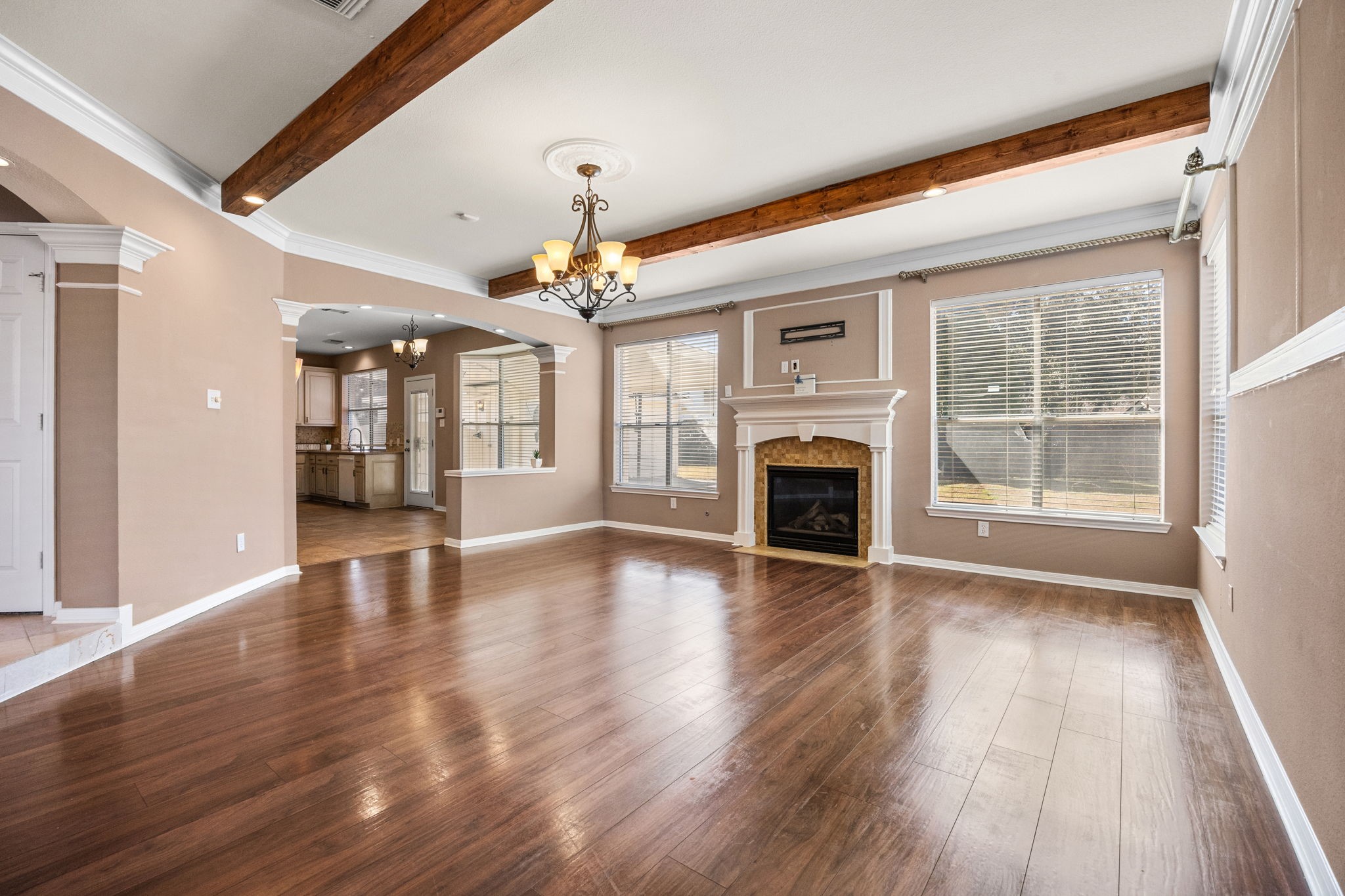 20407 Spring Rose Drive Katy, TX 77450 - Photo 10 of 33 The living room is expansive, offering a warm and inviting atmosphere with its cozy fireplace as the centerpiece. Large windows overlook the backyard, filling the space with abundant natural light and creating a seamless connection between indoor comfort and outdoor views.