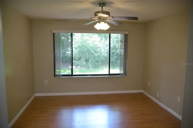 a view of a livingroom with a chandelier fan and wooden floor