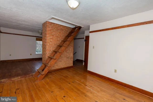 a view of an empty room with wooden floor and white walls