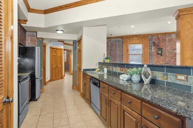 a kitchen with stainless steel appliances granite countertop a refrigerator a stove and a sink